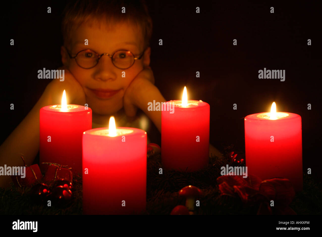 young boy looking at the four burning candles of an Advent wreath
