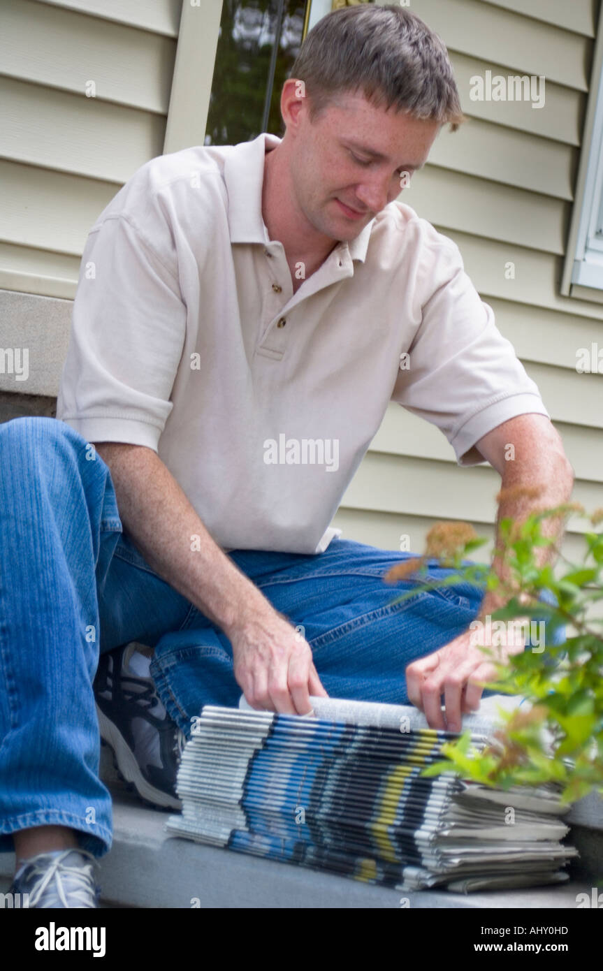 Newspaper delivery person preparing newspapers for paper route Stock