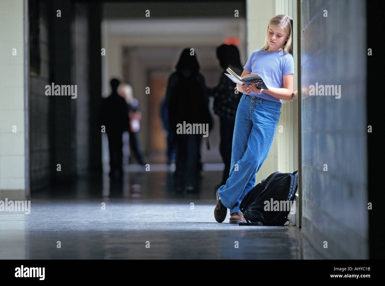 Caucasian female student reading book in middle school hallway Stock Photo