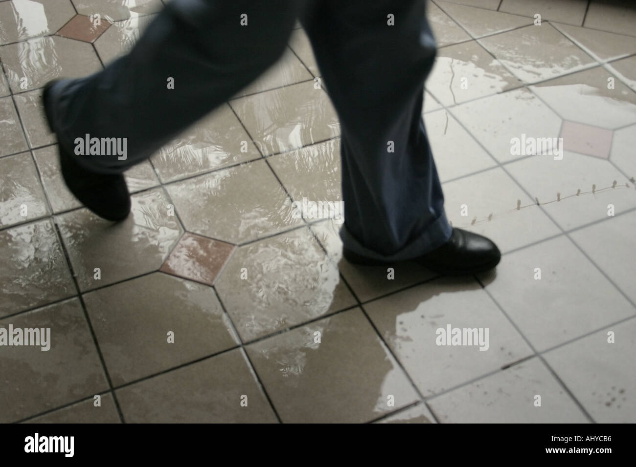 a pair of feet walking on slippery floor wet from rain Wearing blue