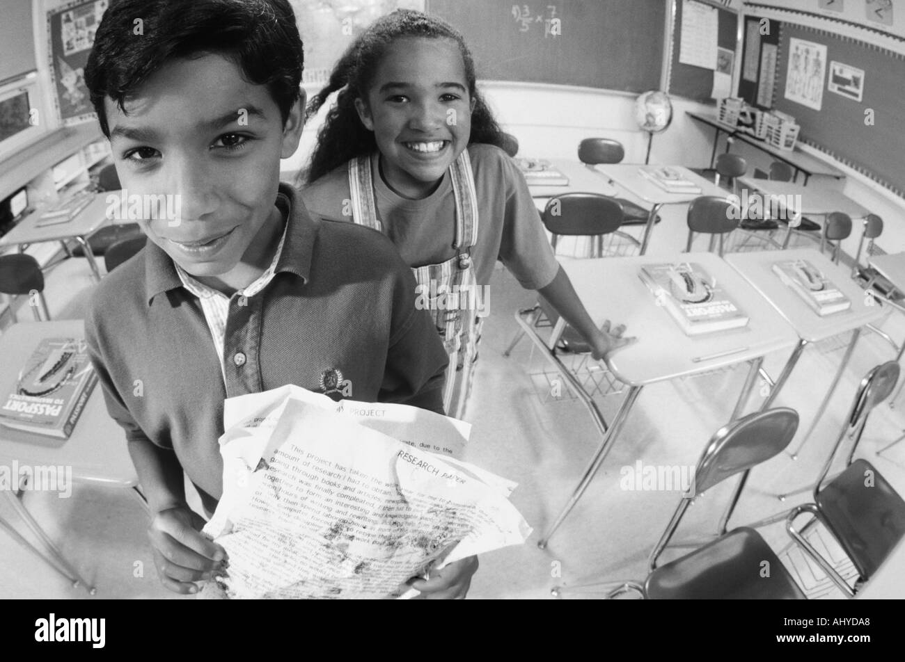 Two Latino middle school students with messy homework papers Using the excuse 'the dog ate my homework' Stock Photo