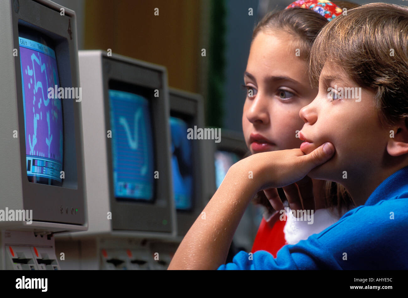 Two Caucasian students concentrating on problem in elementary computer class Stock Photo