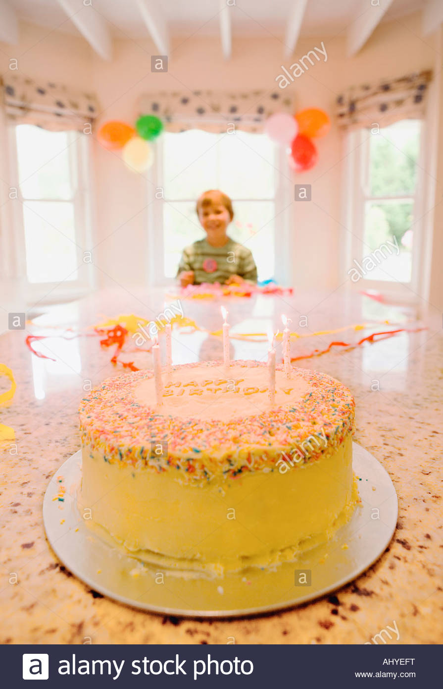 Boy 4 6 Sitting At End Of Table At Home Looking At Birthday Cake