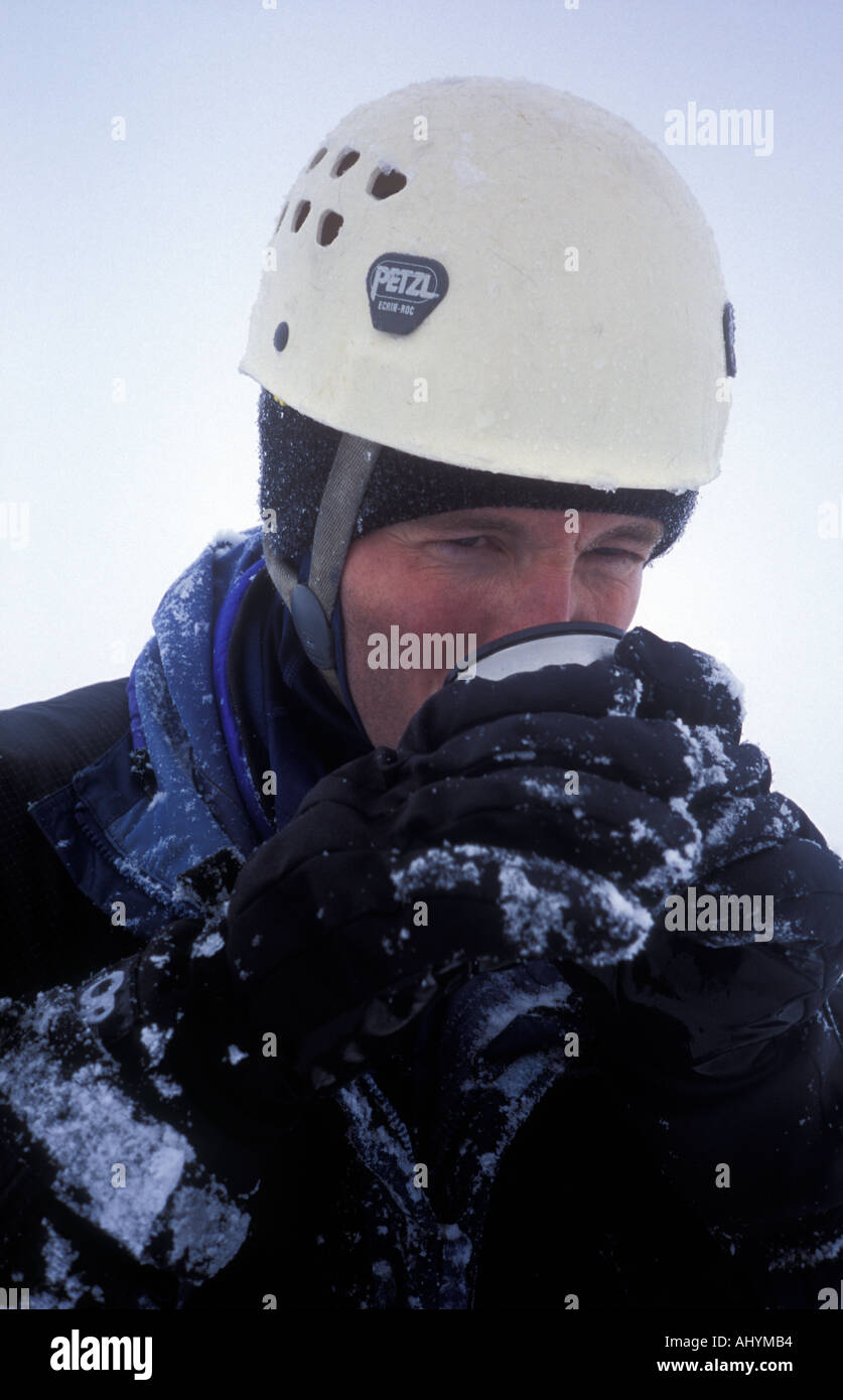 Climber drinking from thermos in wild winter weather on Ledge Route North Face of Ben Nevis Highlands Scotland Stock Photo