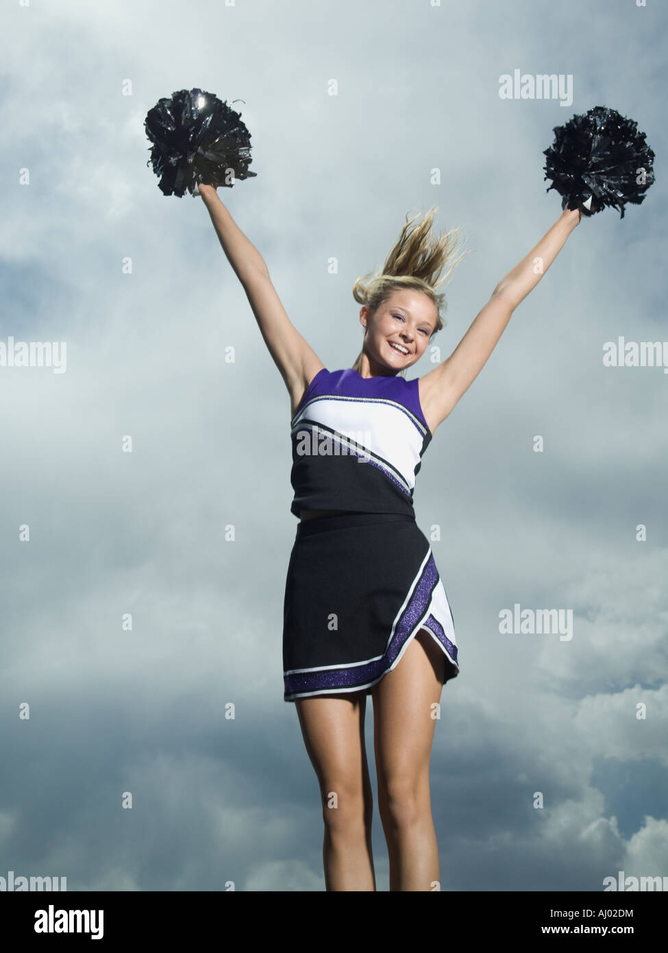 Cheerleader with pom poms jumping Stock Photo