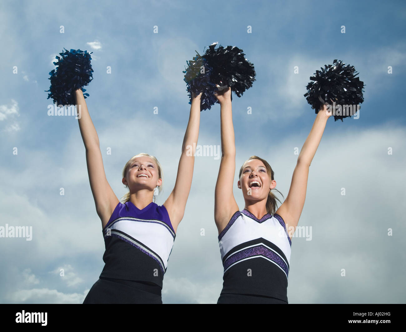 Two cheerleaders holding pom poms over head Stock Photo