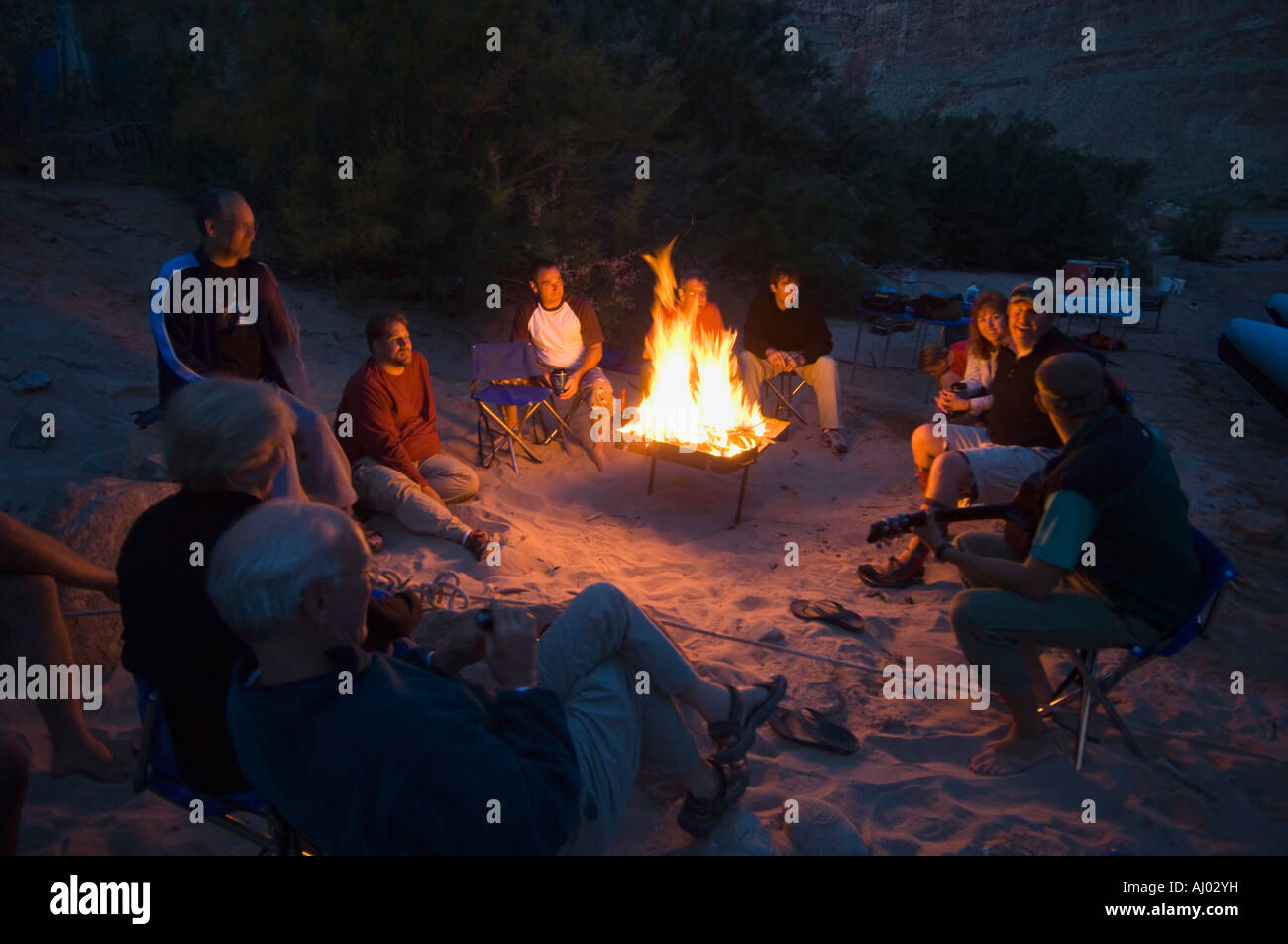 People relaxing around camp fire Stock Photo
