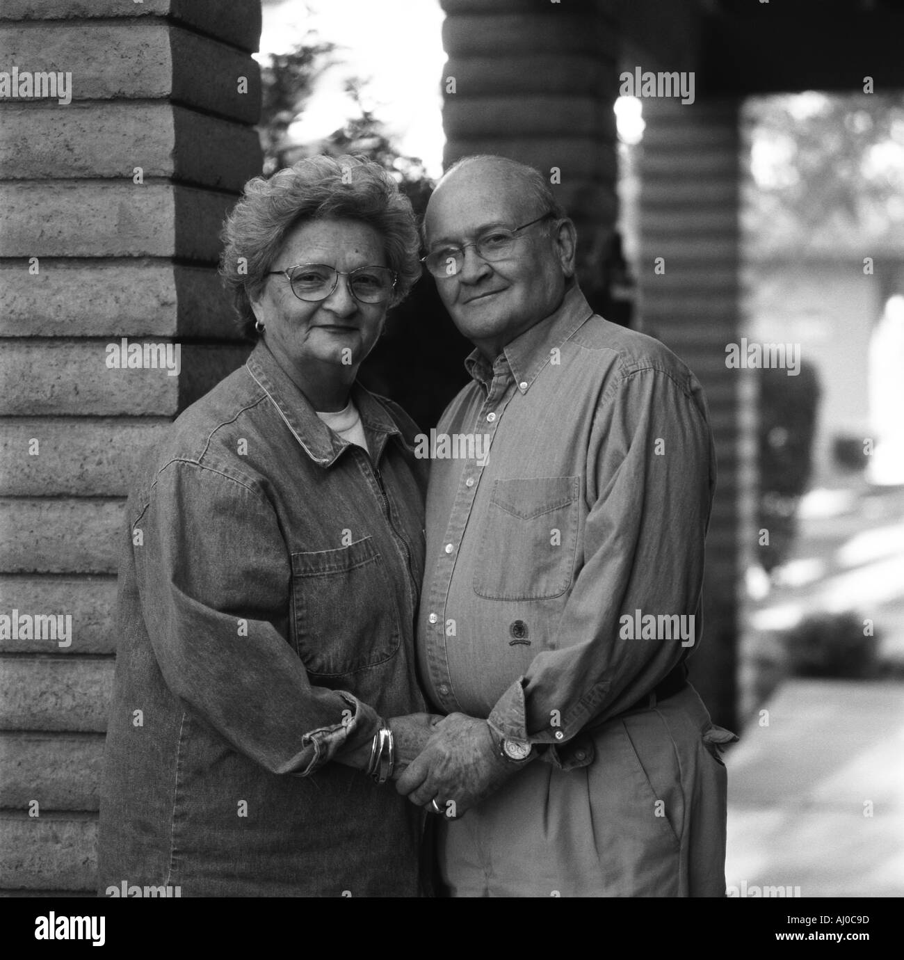 Portrait of a smiling senior couple holding hands while standing outdoors in casual clothes Stock Photo