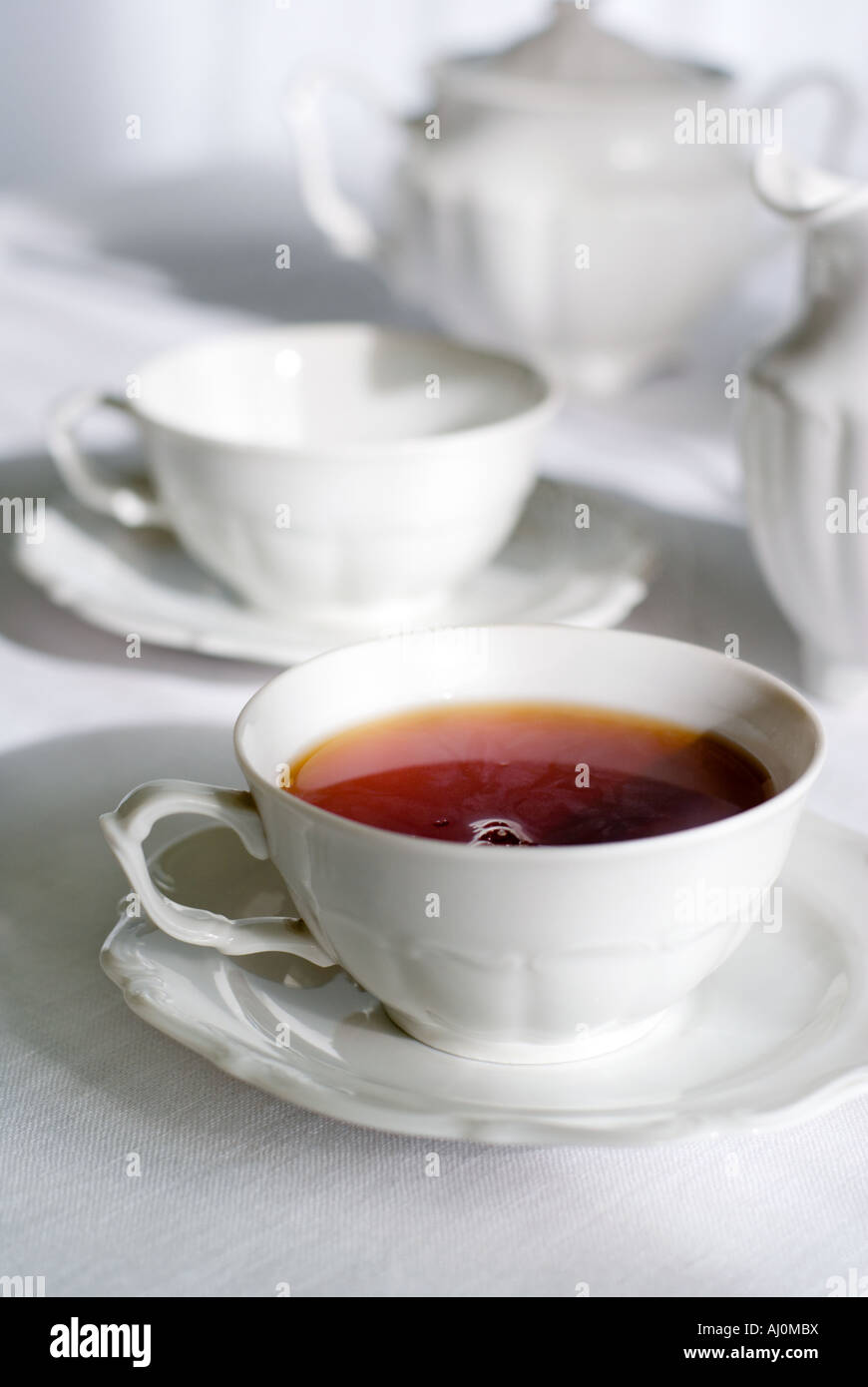 Tea set two teacups one with steaming hot tea sugarbasin behind Focus