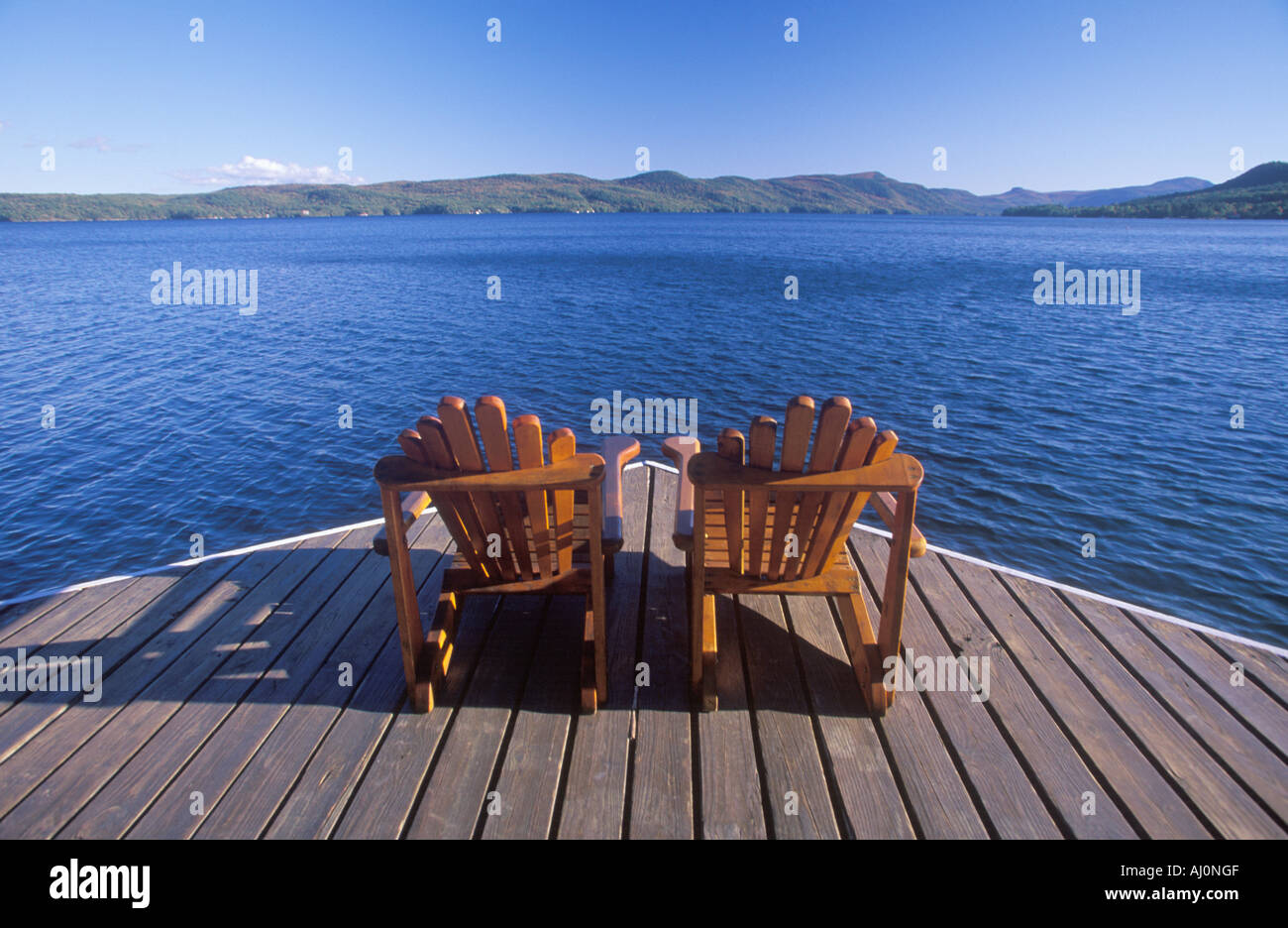 Two Adirondack chairs on a deck overlooking Lake NY Stock Photo