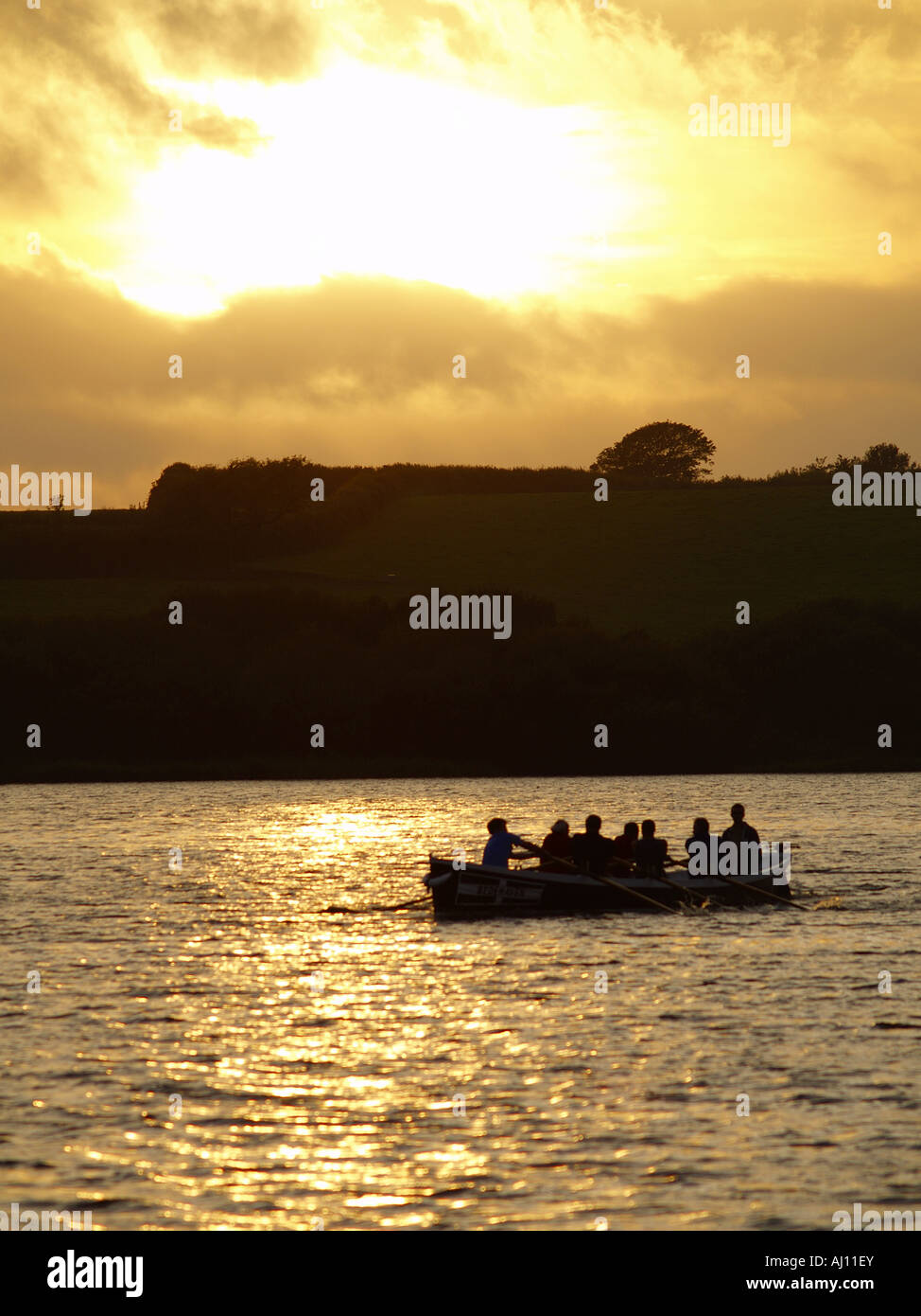 Silhouette of people rowing a boat on Upper Tamar Lakes at sunset, Bude