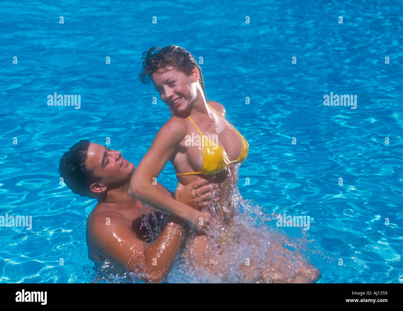 young man lifting young woman in pool Stock Photo