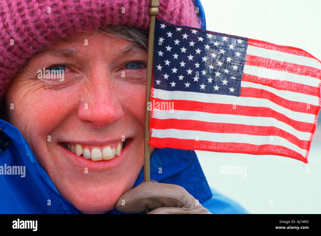 A woman into winter clothing holds a small American flag San Francisco CA Stock Photo