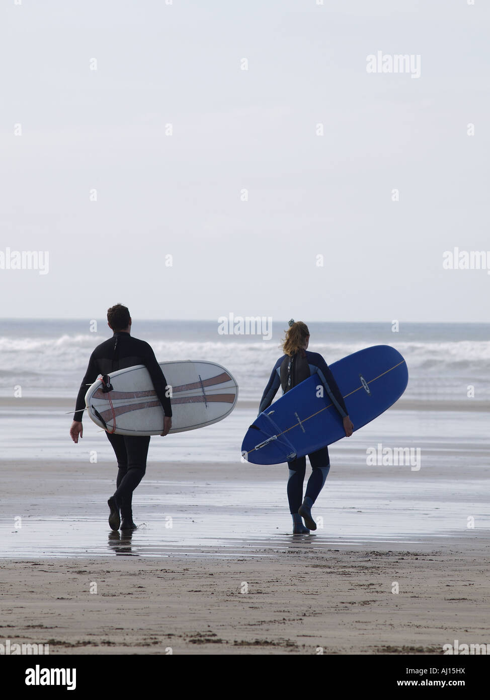 Two surfers walking towards the sea with their surfboards under their arms Stock Photo