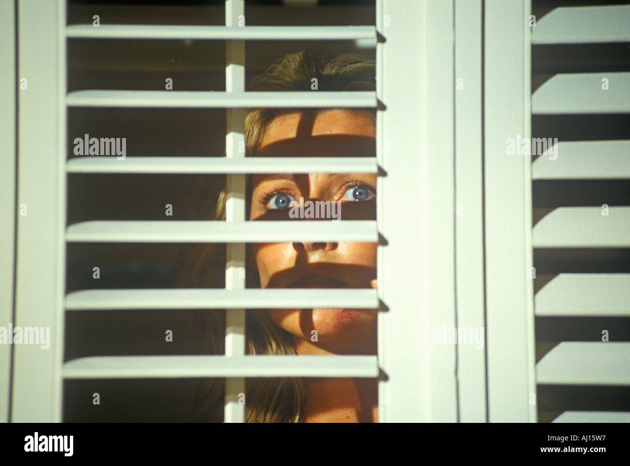Scene with actress looking through blinds from set of Temptation feature film Miami FL Stock Photo
