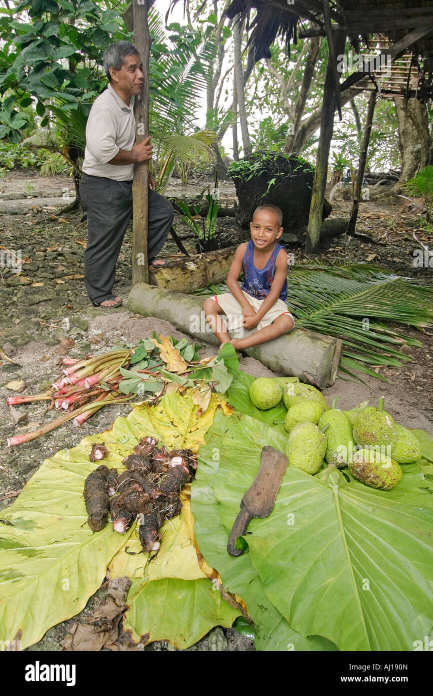 Local Kosrae man and his son cook tropical food in uhm traditional pit oven Stock Photo