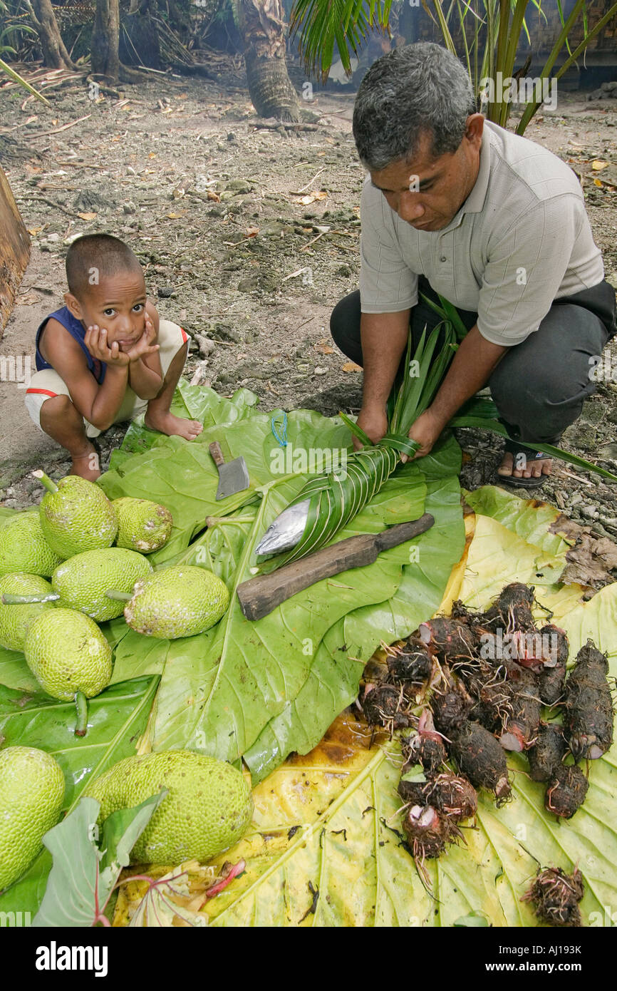 Local Kosrae man and his son cooking food in uhm traditional pit oven Stock Photo