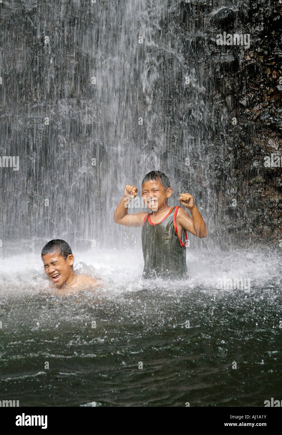 Young native boys play in cascading spray of Sipyen Waterfall in Kosrae Federated States of Micronesia FSM Stock Photo