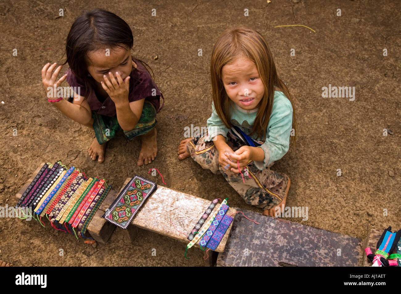 Children selling wrist bands to tourists in Hmong tribal village near Luang Prabang Laos Stock Photo