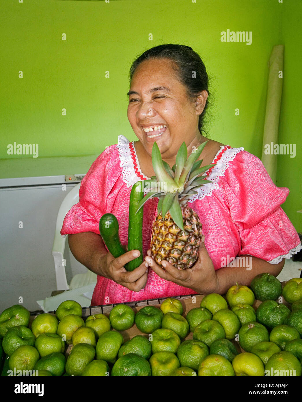 Kosrae woman displays tangerines pineapple and cucumbers she has for sale at her fruit stand in Kosrae Micronesia Stock Photo
