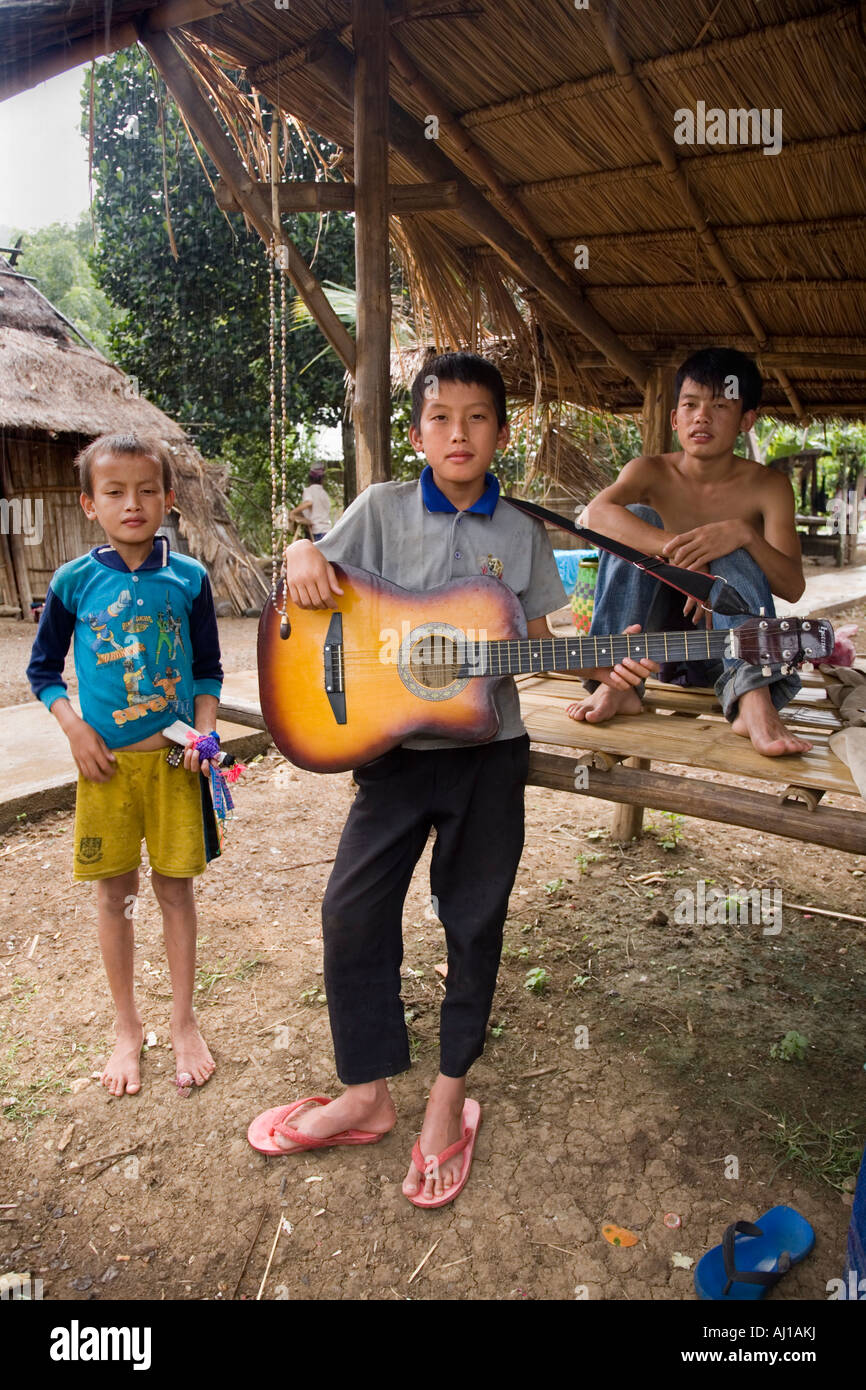 Three boys relaxing with a guitar in Hmong tribal village near Luang Prabang Laos Stock Photo