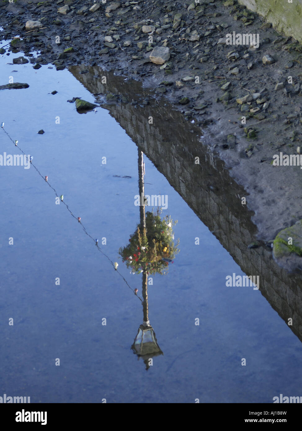 Reflection of a Victorian styled street light with a hanging basket on it, in a river Stock Photo