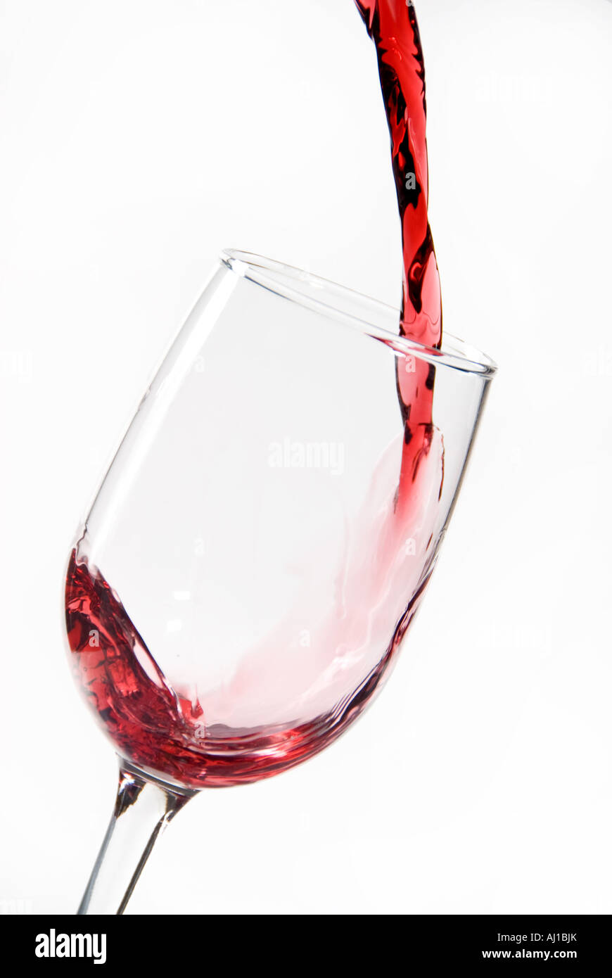 Blood red wine being poured into a clear wine glass for sipping at happy hour Stock Photo