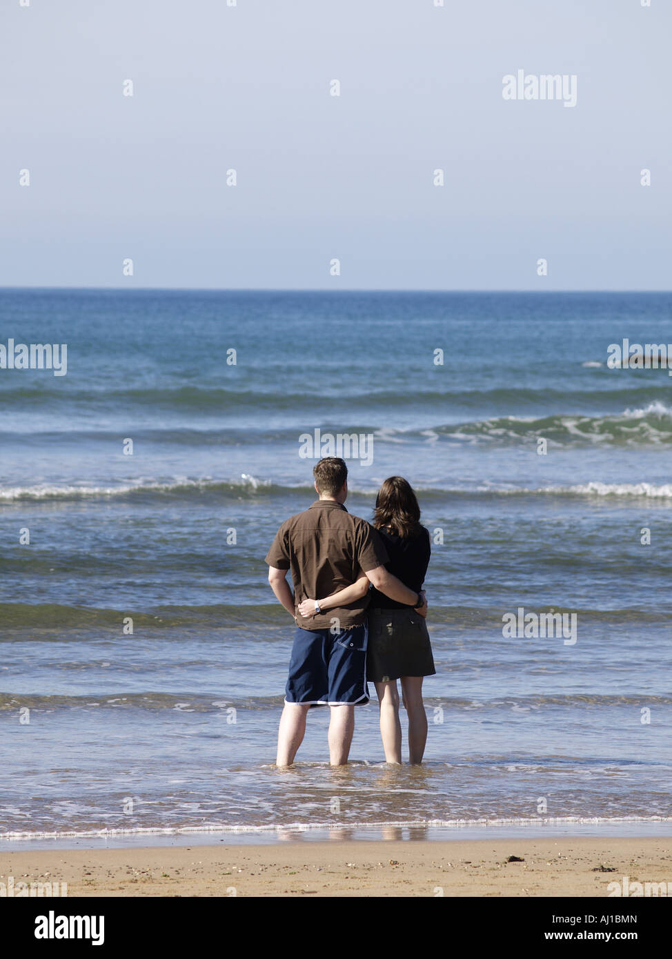 Couple paddling on the edge of the sea, cuddling each other Stock Photo