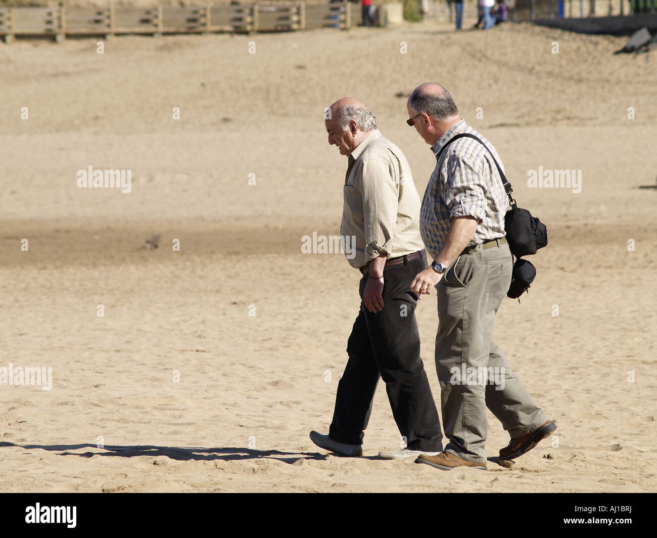 Two old men walking on a sandy beach Stock Photo