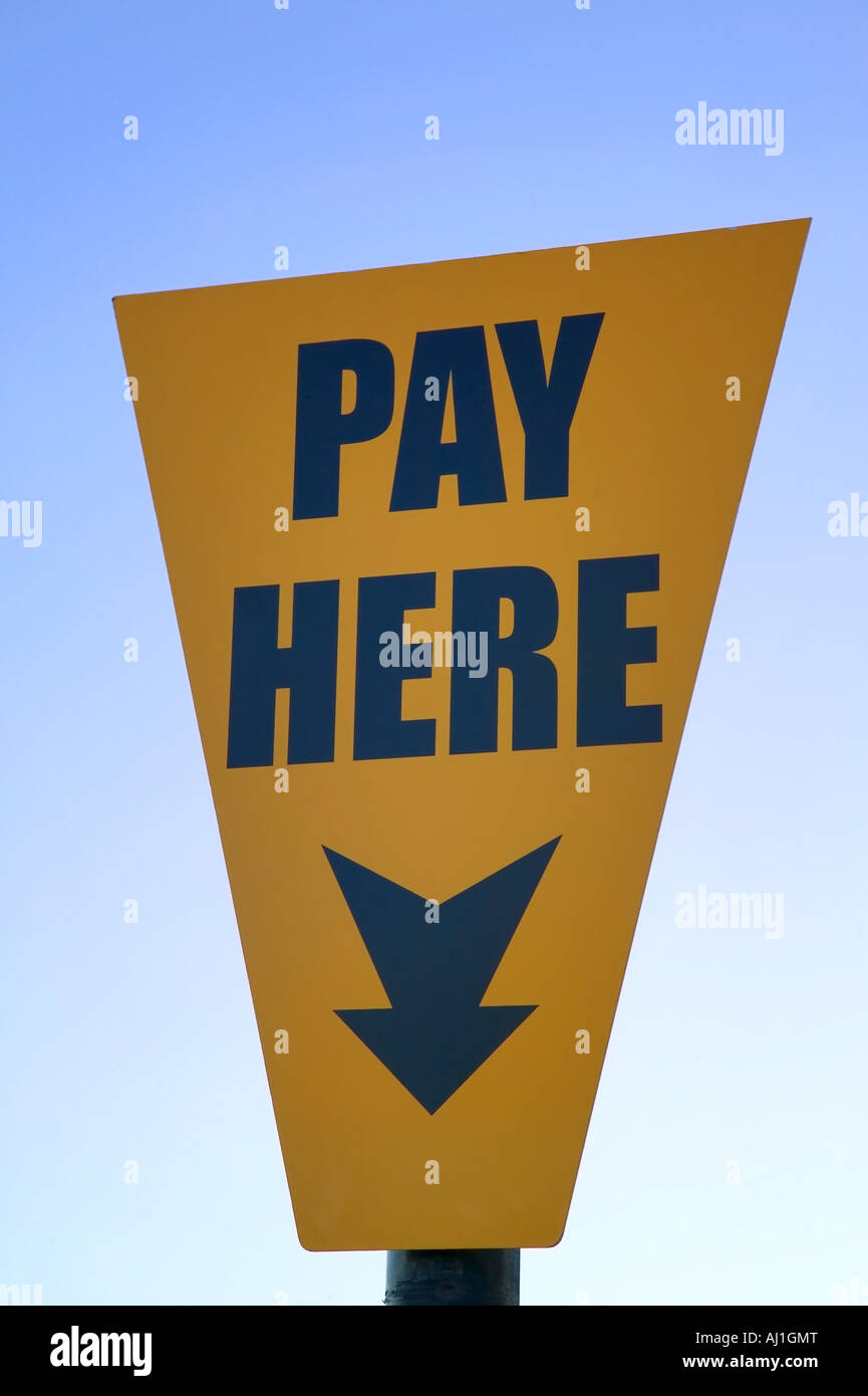 Pay here yellow sign against a blue sky Stock Photo