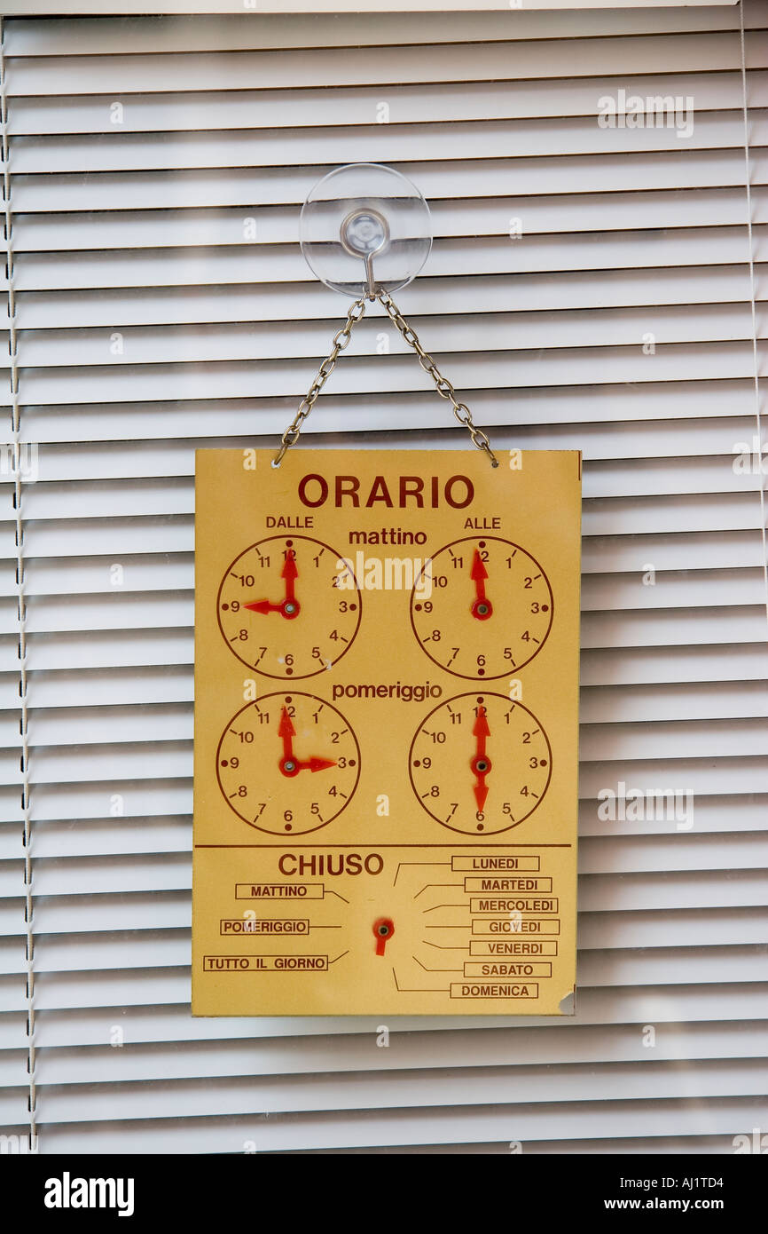 Hours of opening or operation hangs from window in shop Venice Italy Stock Photo
