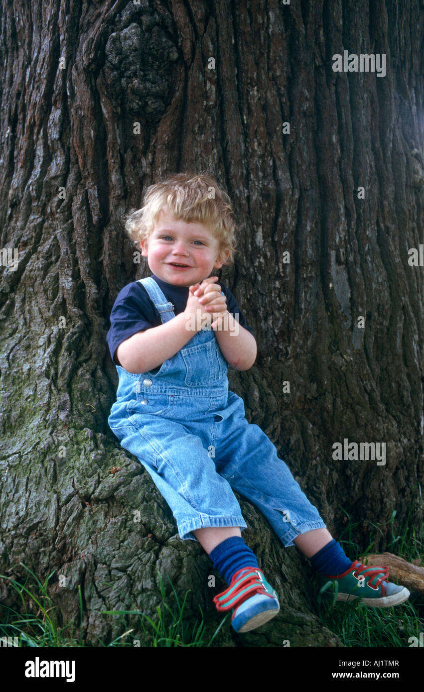 happy little boy seated under tree Stock Photo Alamy