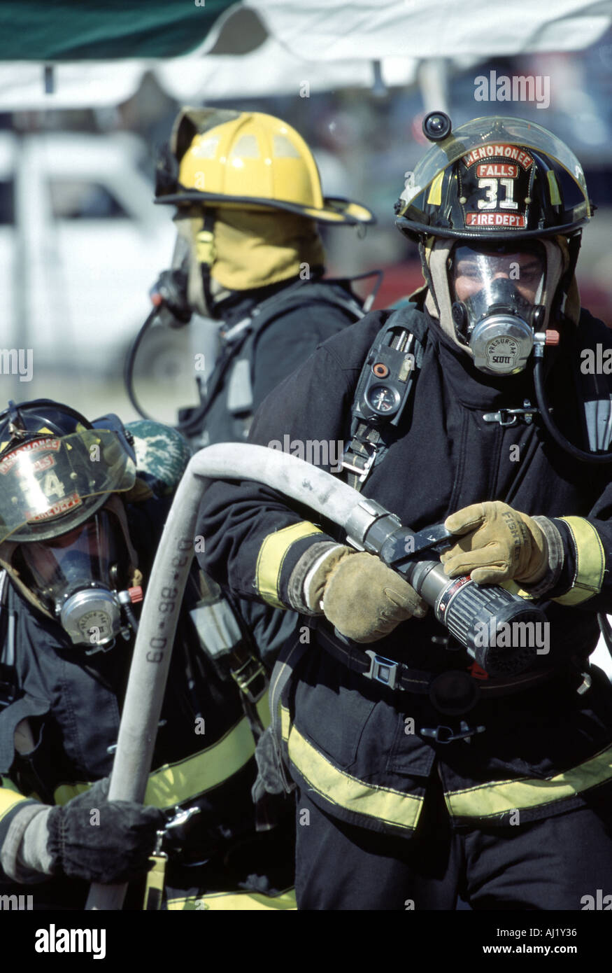 Three fire fighters holding a hoseline getting ready to use it on a fire at a scene Stock Photo