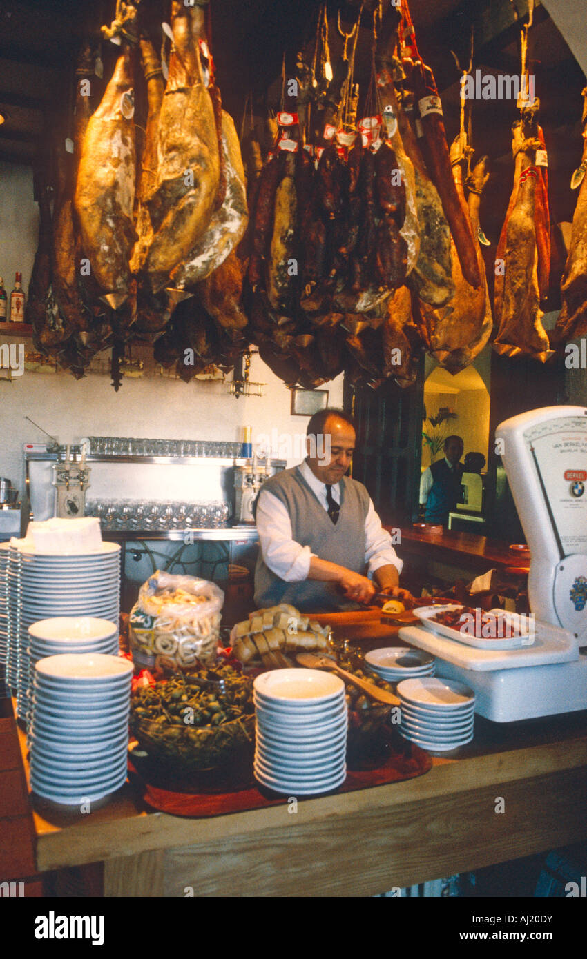 restaurant Madrid showing man preparing tapas hams hanging Stock Photo