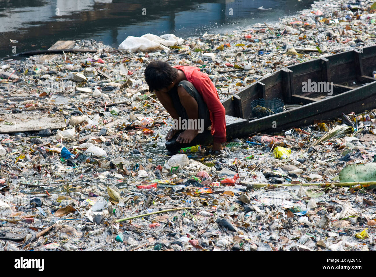 Young Man Picking through Ciliwung River of Garbage for Scraps of Value Jakarta Indonesia Stock