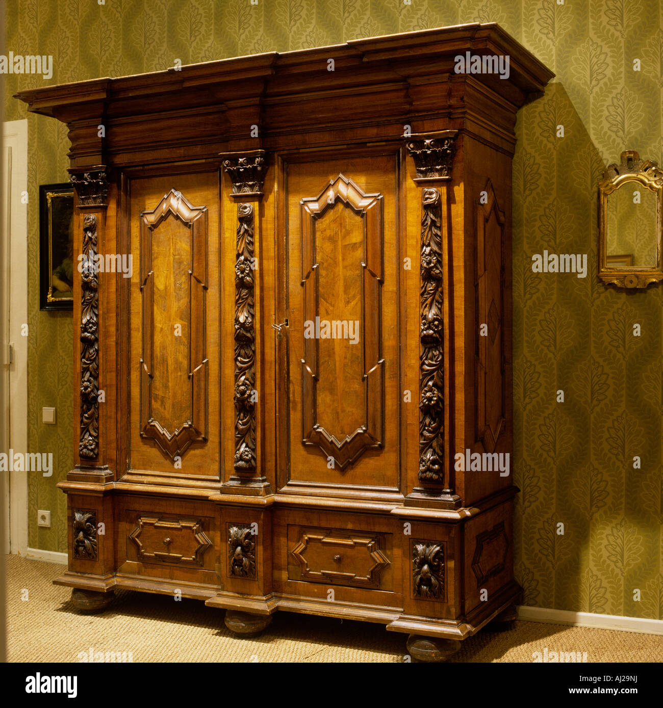 Ornate antique wooden wardrobe with green patterned wallpaper behind in  historic German stately home Stock Photo - Alamy