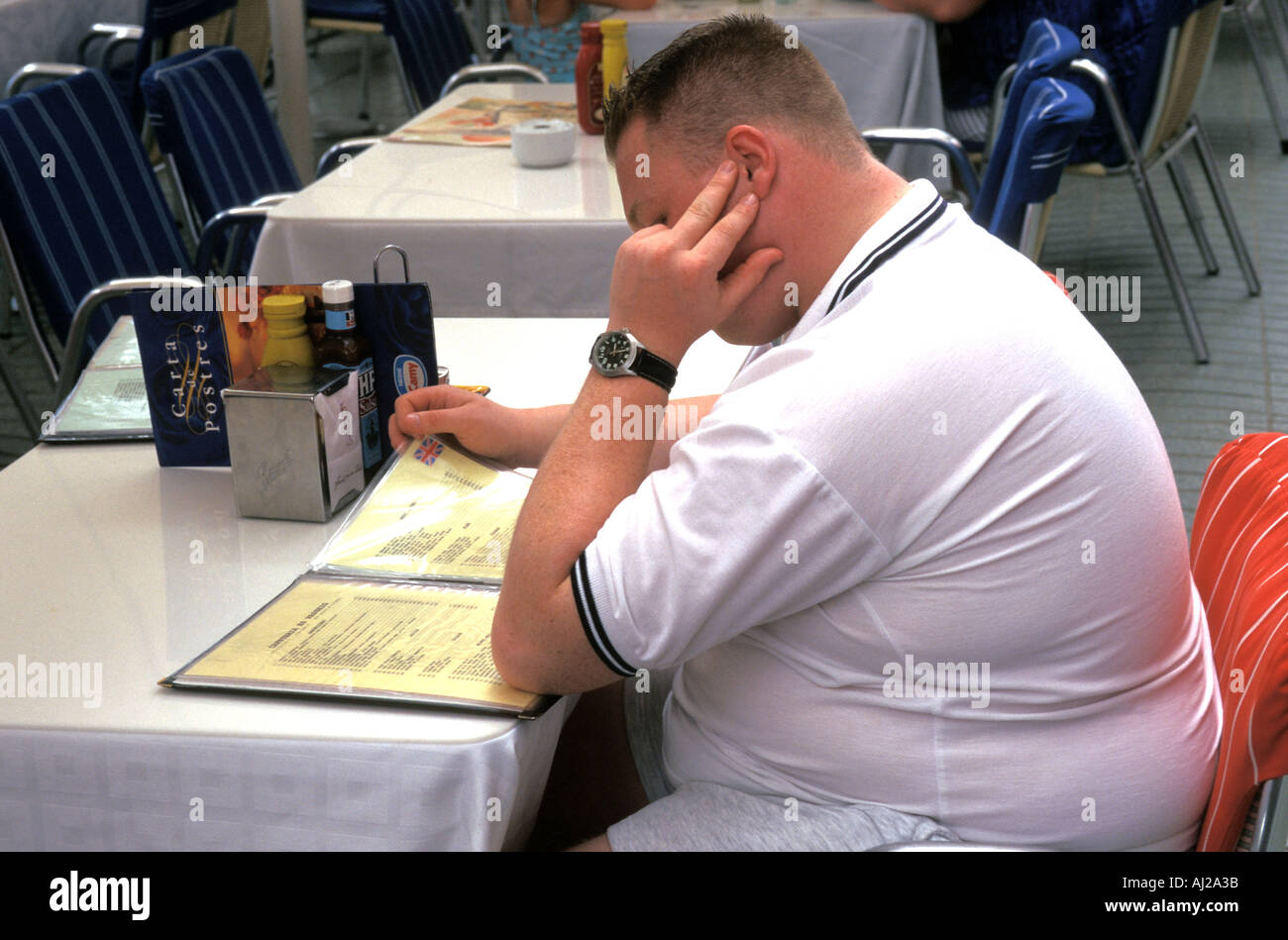 Young obese British man reading restaurant menu in Ibiza, Spain Stock Photo