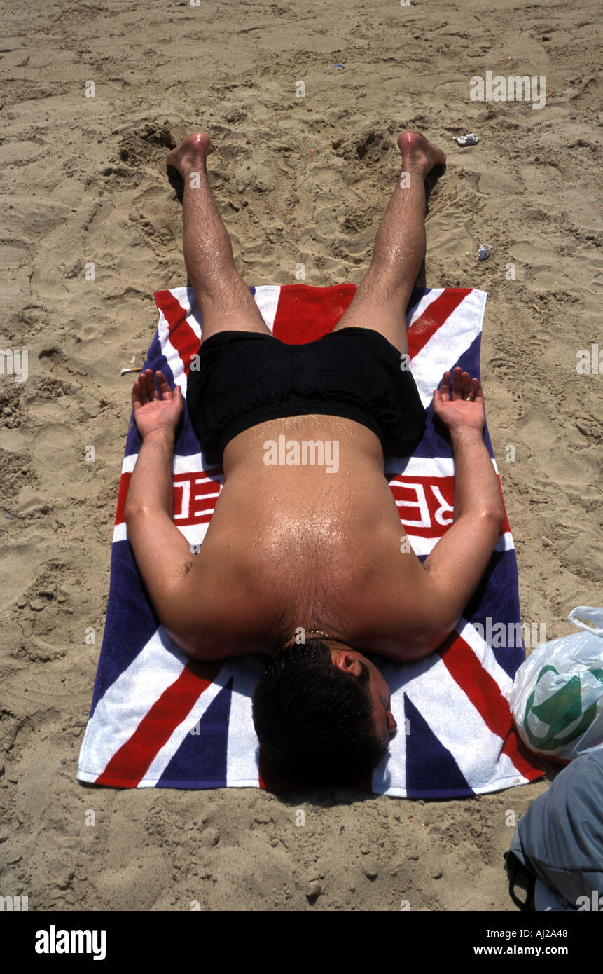 Sunbathing on Union Jack towel on the beach in Ibiza, Spain Stock Photo