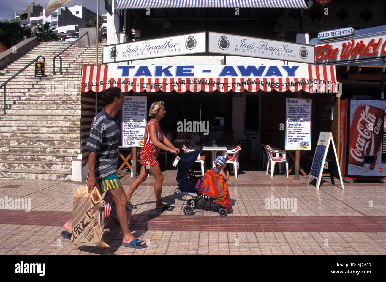 English holidaymakers pass fast food takeaway at Playa de las Americas