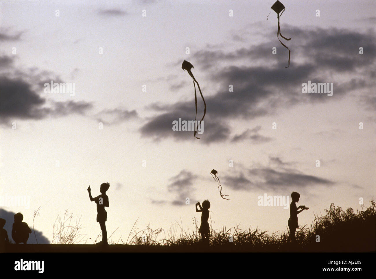 Children flying kites on a hill in Phnom Penh Cambodia at dusk. Stock Photo