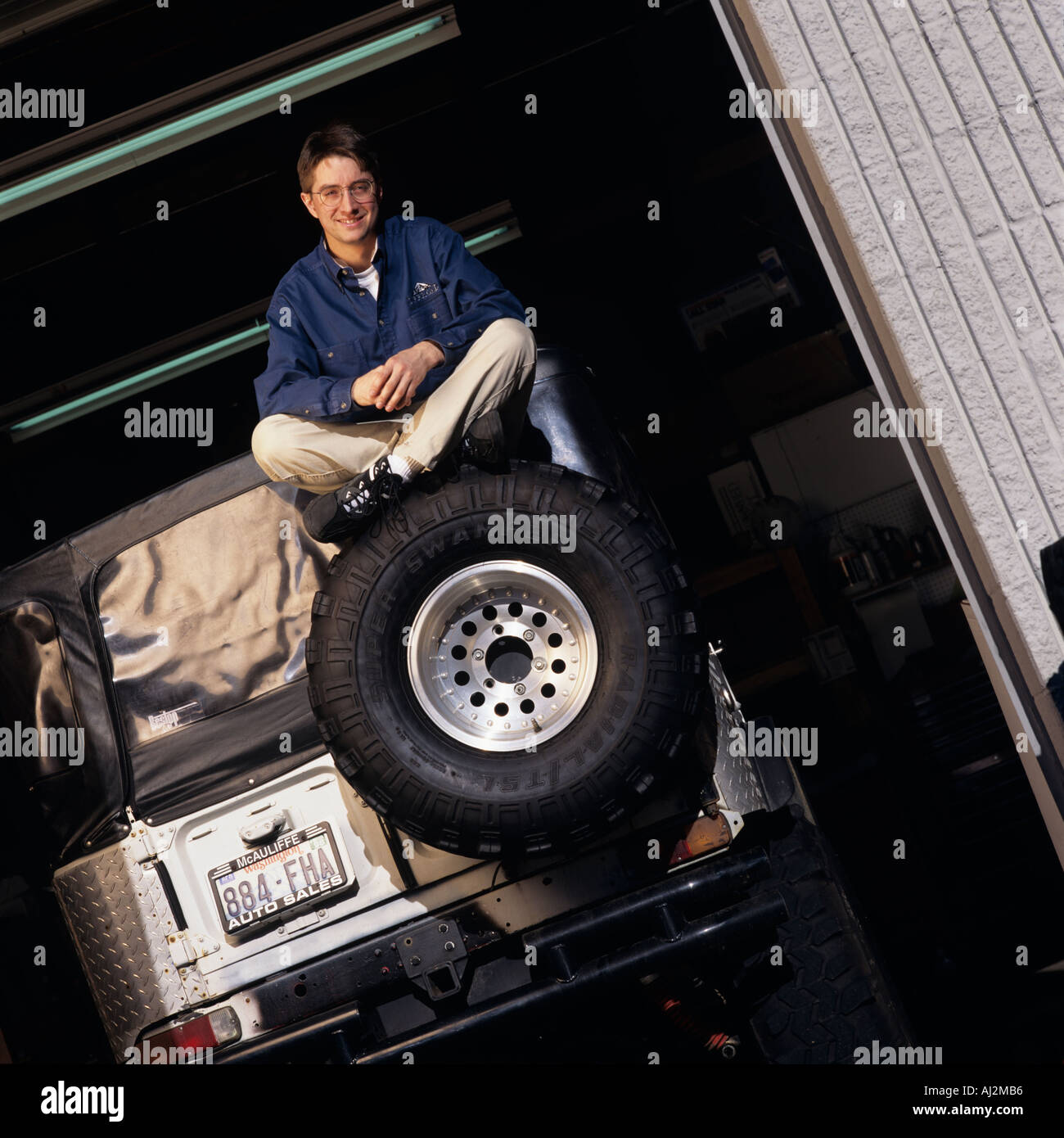 USA Washington Redmond MR Portrait of Kevin Wyman sitting atop modified 4WD truck outside Offroad Outlet auto parts store Stock Photo