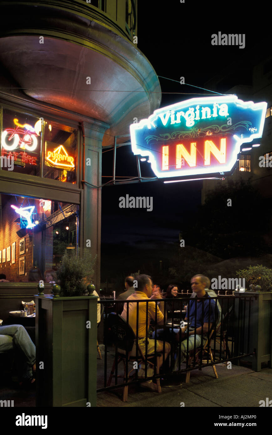 USA Washington Seattle Restaurant patrons sit outside the Virginia Inn s neon signs on summer evening Stock Photo