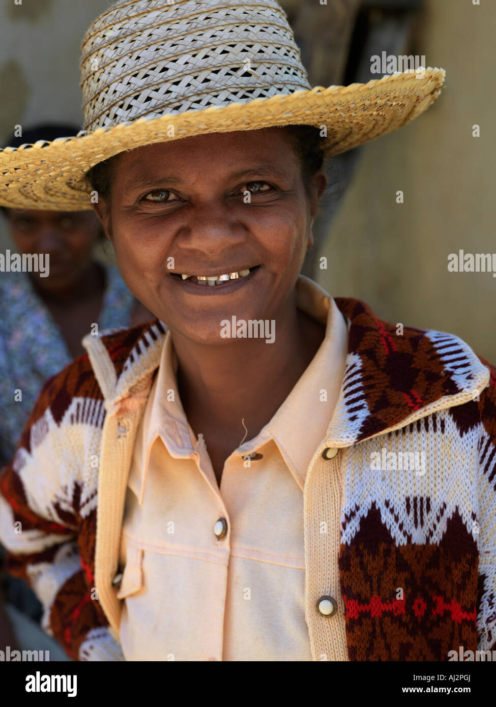 A woman in a Malagasy hat shows her gold-capped teeth when she smiles. Gold teeth are a sign of wealth. Stock Photo
