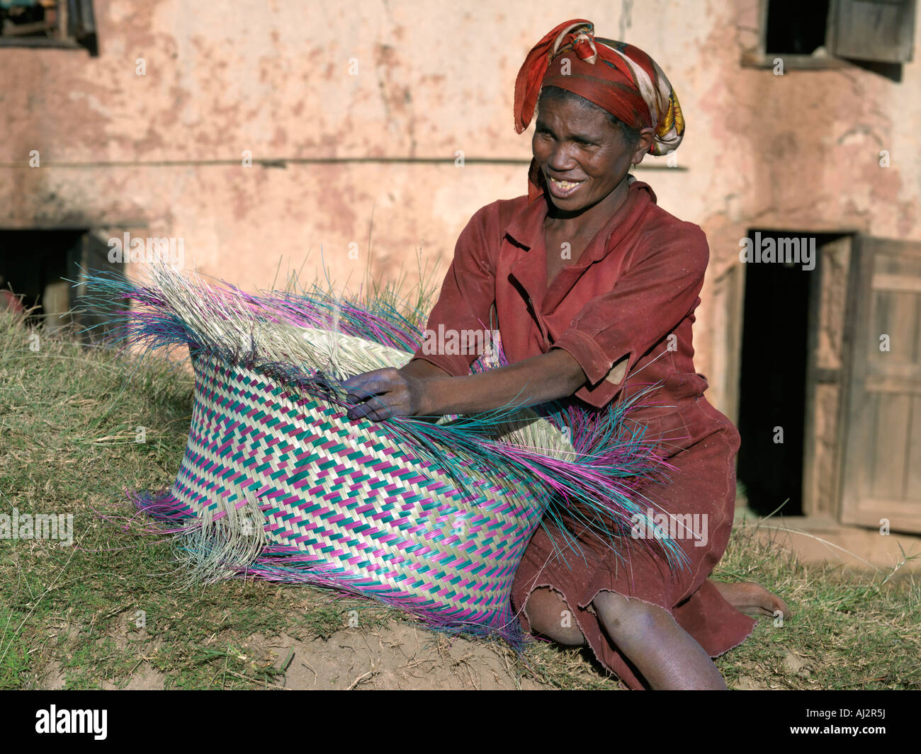 A Malagasy woman weaves a basket from raffia palm. Stock Photo