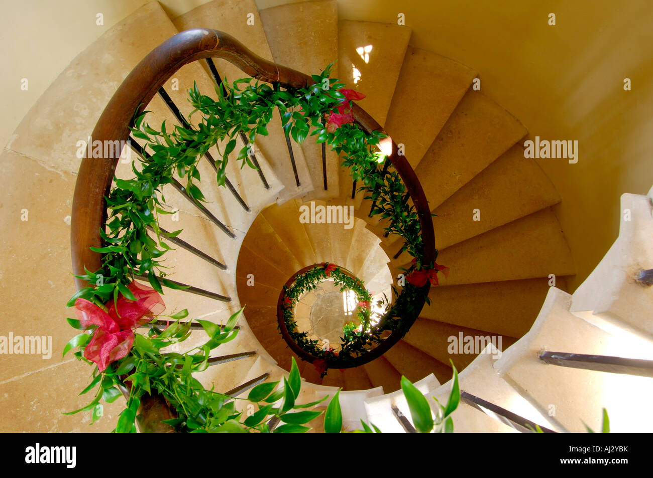 A spiral stone staircase with a wooden banister decorated with leaves and flowers for a wedding ceremony Stock Photo