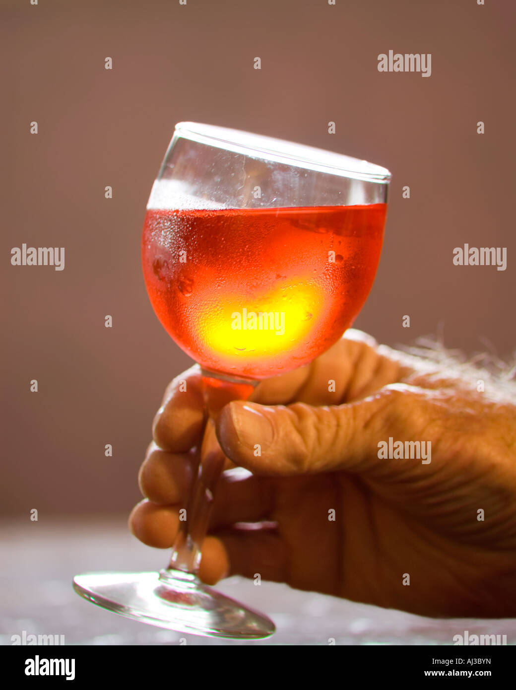 A glass of red wine in an elderly man's hand. USA. Stock Photo