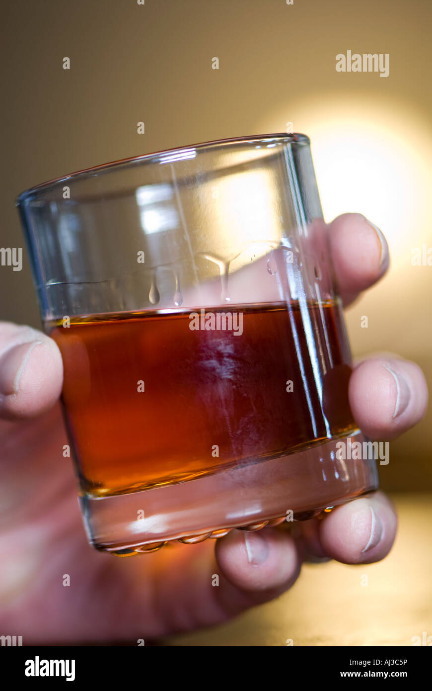 Shot glass of whiskey  in Caucasian man’s hand. Stock Photo