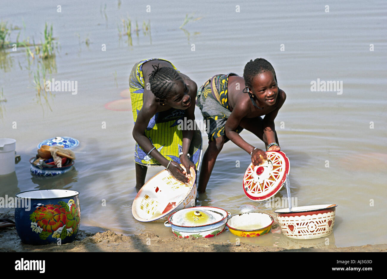 Young girls from the Bozo tribe washing dishes in the River Niger at Dagua Womina, Mali Stock Photo