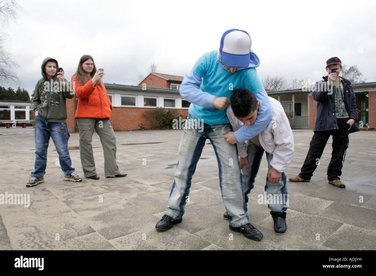 two fighting boys are being filmed by three other teenagers with their mobile phones Stock Photo