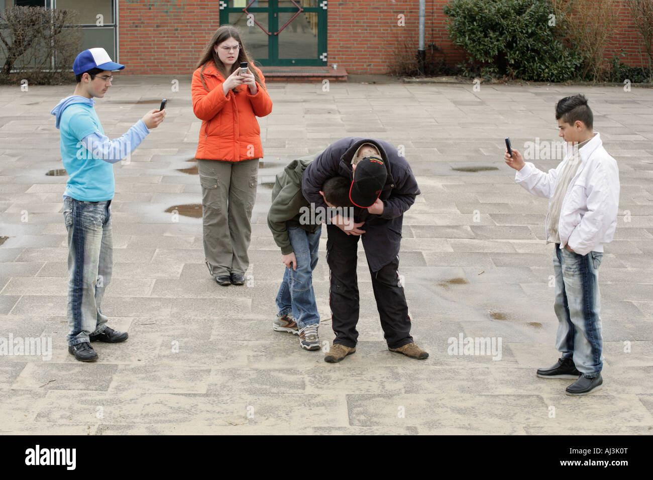 two fighting boys are being filmed by three other teenagers with their mobile phones Stock Photo